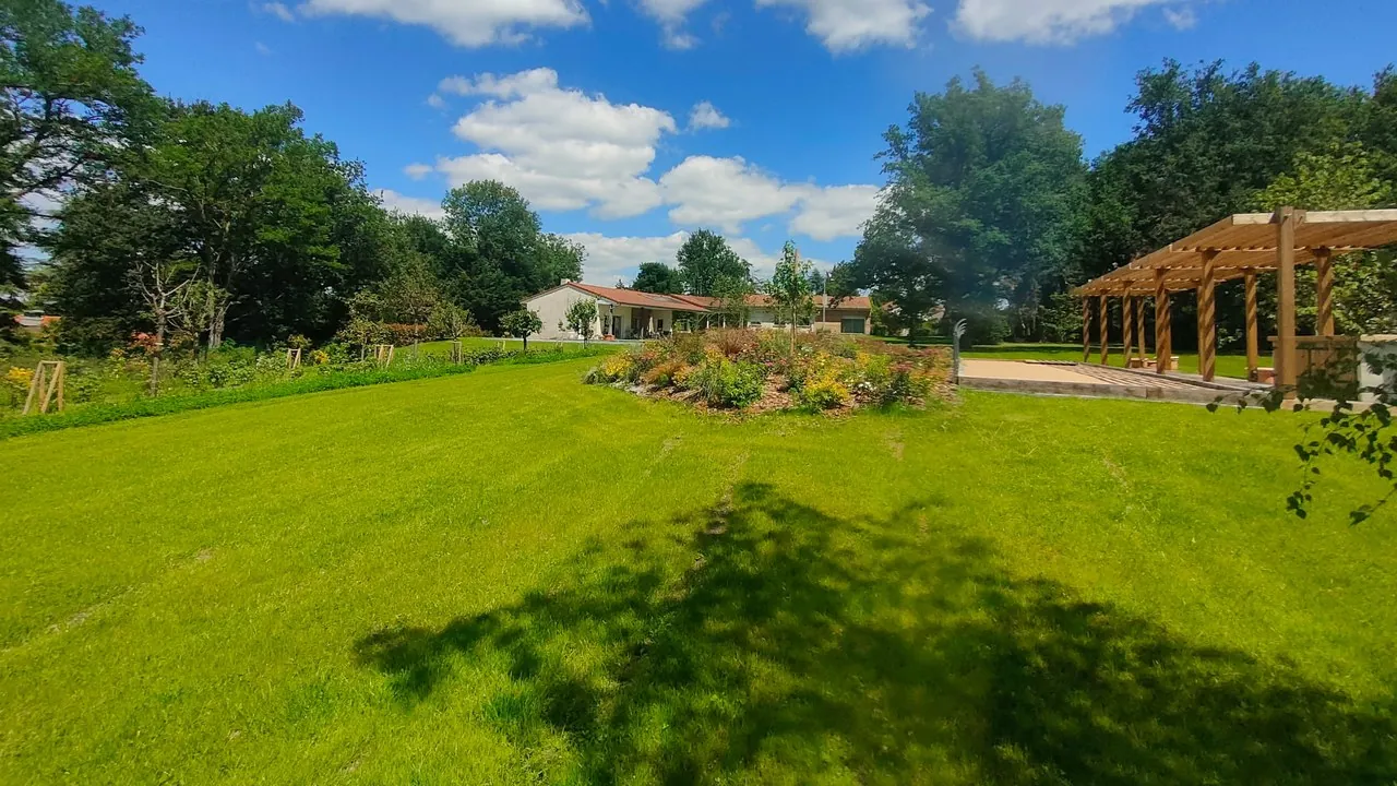 Parc réaménagé : grande pelouse, massif fleuri et pergola bois