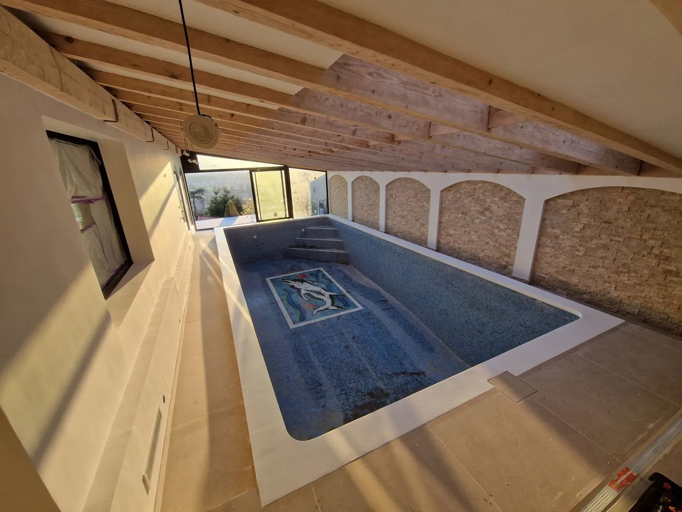 Piscine intérieure en mosaïque avec parement pierre.