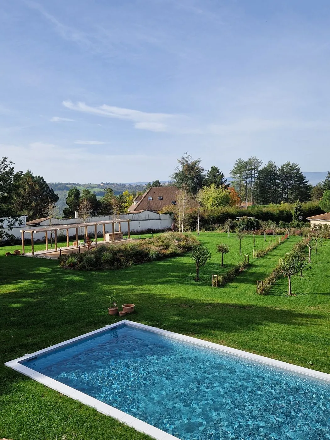 Grand jardin avec piscine, pergola et verger.